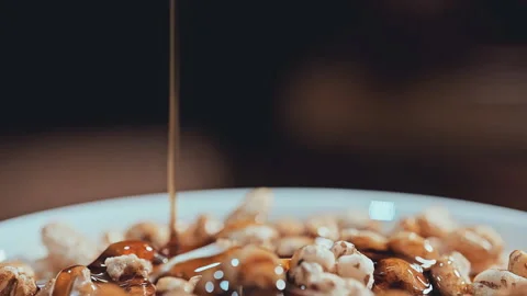 Amber Syrup Drizzling on Crispy Puffed Cereal Close-up Stock-Footage 335895149