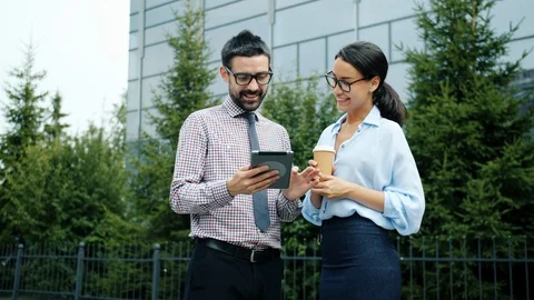 Ambitious entrepeneurs discussing business outside and working with tablet Vídeos de archivo