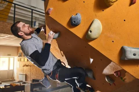 Ambitious physically challenged boulderer climbing artificial rock wall Stock Photos