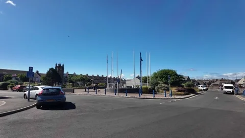 Amble town's central roundabout featuring a sundial monument under a clear blue Stock Footage 341031371