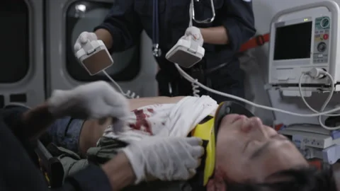 Ambulance crew using defibrillator for unconscious patient Video stock 164033928