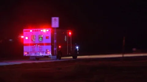 Ambulance drives down long road at night with flashing lights 動画素材 72242990