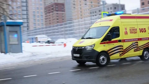Ambulance featuring yellow body with red stripes and 103 marking navigates Stock Footage 326204777
