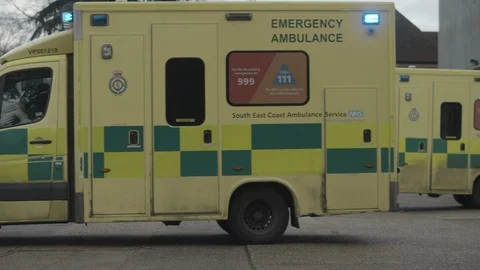 An ambulance with lights flashing pulling away on an emergency call in Stock Footage 124418831