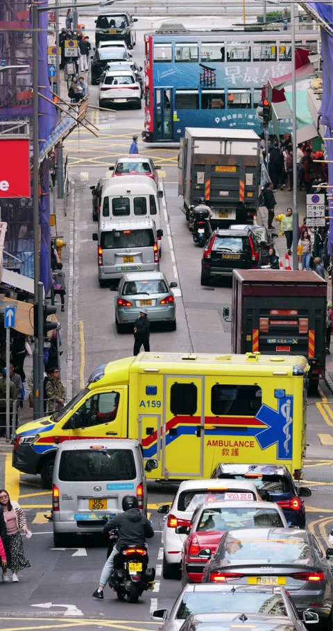 Ambulance navigating through busy Hong Kong traffic, telephoto view Stock Footage 309363439