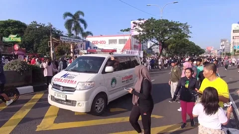 An ambulance passes through the crowd attending the Depok Car Free Day event Stock Footage 310157674