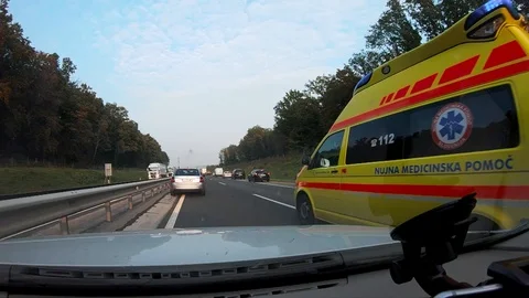 Ambulance with rescuers rushing past car... | Stock Video | Pond5