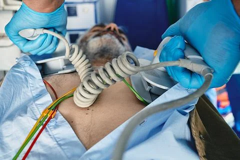 Ambulance worker using portable defibrillator in attempt to revive senior m.. Foto stock