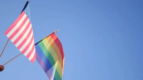 American and LGBT flag on blue sky Stock Footage