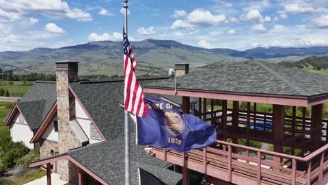 American and Oregon state flags fly above a rustic stone welcome center rooftop Stock Footage 337513949
