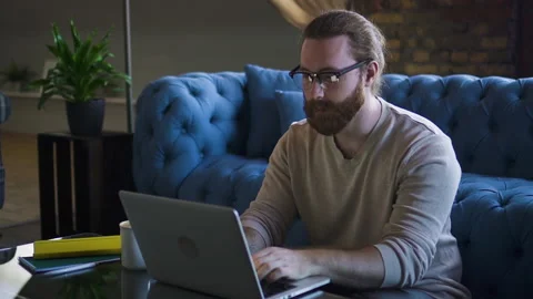 American bearded guy hipster is working with laptop while sitting at table in Stock Footage 134869852