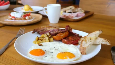 American breakfast with sunny side fried eggs, bacon, tomatoes, bread toasts Stock Footage 191455261