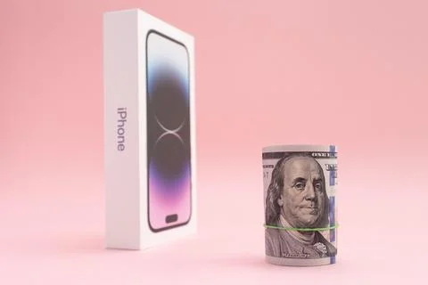 American dollars in roll, box of device iPhone 14 Pro deep purple coloron pink Foto stock