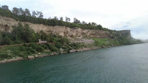 American Falls at the head of the Niagara Gorge with wooded limestone cliffs Stock Footage 345996035
