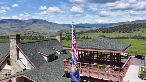 American flag and state flag fly above stone-chimney welcome center roof in Vídeo Stock 338984066