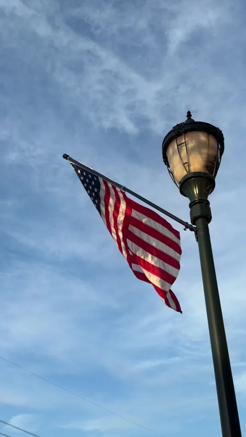 American flag attached to a lamp post blows in the wind Stock Footage 337497866