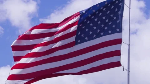 American flag blowing in stiff wind under blue skies 스톡 동영상 84084978