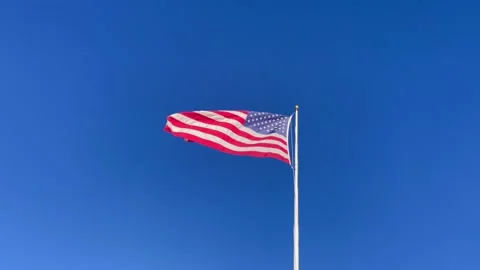 American flag blowing in the wind on the blue sky background Stock Footage 221163582