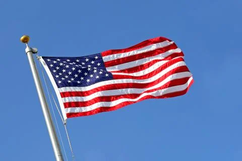 American flag blowing in the wind with blue sky Stock Photos