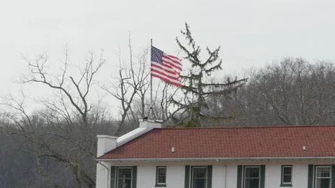 American flag blowing in the wind on top of a building in slow motion winter fal Stock Footage 232977138