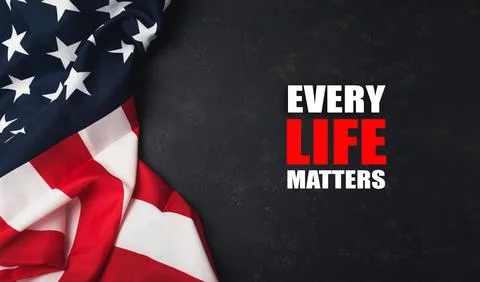 American flag draped on dark surface with bold text stating every life matters, Stock Photos