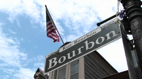 An American flag flies above a street sign identifying Bourbon Street Stock Footage