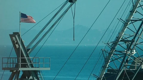 American Flag flies on a construction crane overlooking San Francisco Bay Stock Footage 95699731