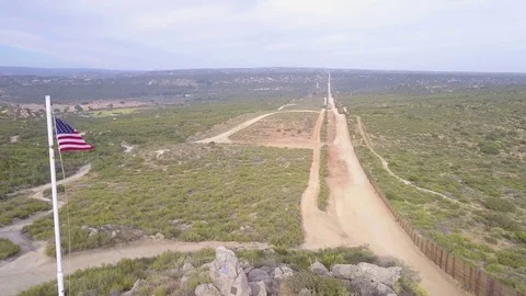 The American flag flies over the U.S. Mexico border in the California desert. Stock Footage 79400181
