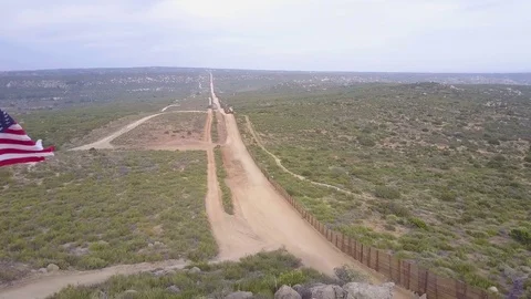The American flag flies over the U.S. Mexico border wall in the California Video stock 79501487