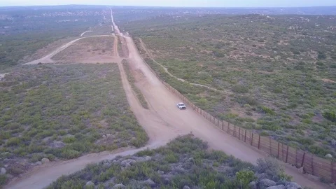 The American flag flies over the U.S. Mexico border wall in the California Stock Footage 79501556