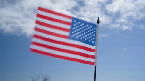 The American flag fluttering in the wind against the backdrop of a blue sky. Stock Footage 269817028