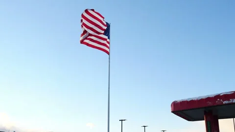 American flag flying from a flagpole against a blue sky Stock Footage 171908782
