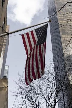 An American flag flying in front of a backdrop of towering skyscrapers on a c Stock Photos