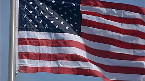 American Flag flying in strong breeze on sunny day Stock Footage 268879880