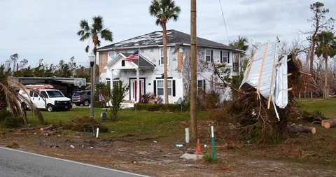 American flag fly's in front of damaged house, siding and shingles blown off Stock Footage 99206458