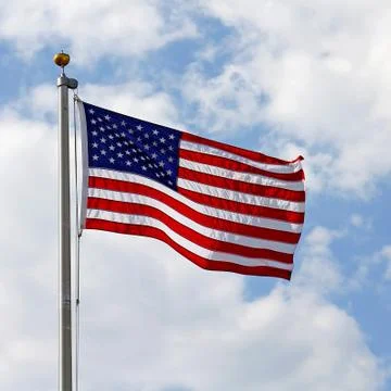 American flag in front of cloudy blue sky Stock Photos