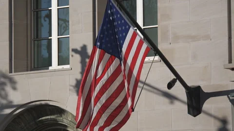American flag hanging from a pole attached to a stone building facade. Stock Footage 327023227