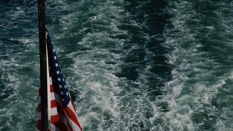 An American Flag hovers over the wake of a boat. (POV from Rear of boat) Stock Footage 89669747