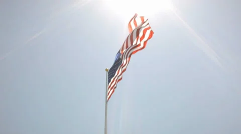 American Flag low angle against blue sky and bright sun with lens flares Stock Footage 38030080