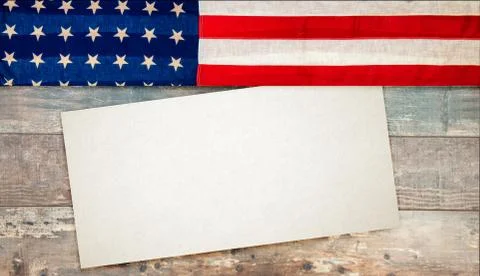 American flag lying on an aged, rustic wooden background with a paper card Stock Photos