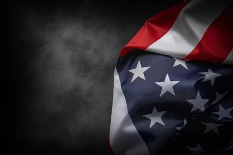 American flag partially folded in dramatic lighting against a dark background Stock Photos