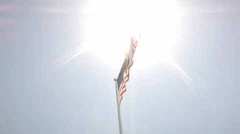 American Flag steadily flapping against bright, enveloping, sun and blue sky Stock Footage 38030533