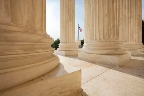 American flag viewed between columns of supreme court building Stock Photos