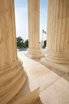 American flag viewed between pillars of supreme court building Stock Photos