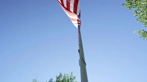 American flag waves against clear blue sky as seen from below looking up Stock Footage 202222899