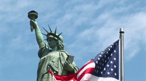 The American flag waves in the foreground with the Statue of Stockbeeldmateriaal 438695