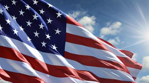 American flag waves gracefully against a bright blue sky with sunlight Stock Footage 315554844