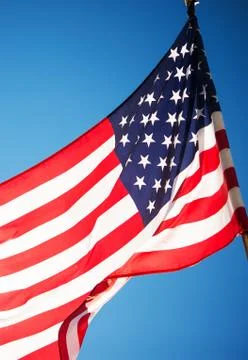 American Flag Waves on Wind. Clear Blue Sky Background. Stock Photos