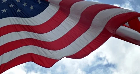 American Flag waving against a cloudy blue sky. 4K 60 fps Stock Footage 111539166