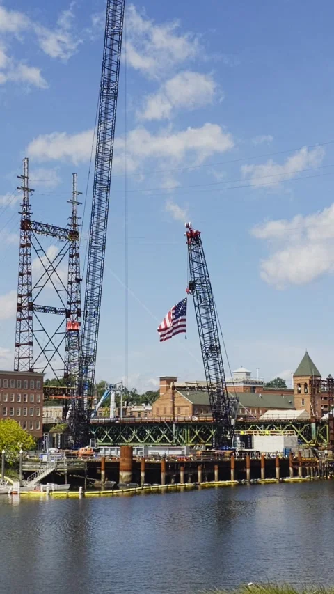 American flag waving from construction crane at bridge building site Stock Footage 344806616